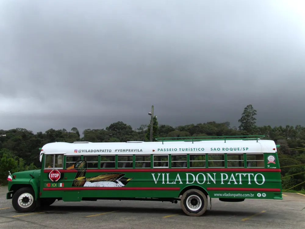 Ônibus turístico verde da Vila Don Patto estacionado sob céu nublado